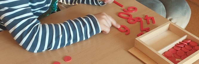 Kinderhände zeigen auf rote Ziffern und Chips, die auf einem Tisch angeordnet sind