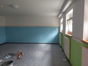 Ein leerer Garderobenraum mit Fliesenboden und hellblauer Wand. 