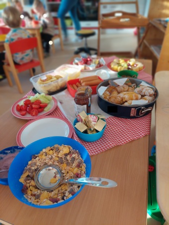 Auf einem Tisch stehen Schüsseln, Teller und Kuchenbleche mit verschiedenstem Obst, Gemüse und Gebackenem.