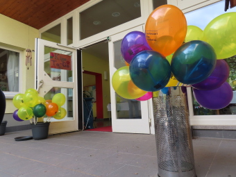 Offenen Kigatür, davor stehen bunte Luftballons