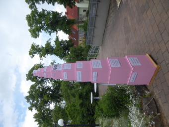 Ein Turm aus rosa Kuben, welche von groß nach klein gestapelt sind, stehen im Garten. 