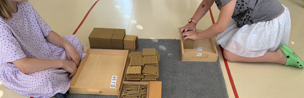 Kinder sitzen am Boden und arbeiten mit dem goldenen Perlenmaterial