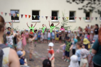 Viele Kinder stehen in einem Kreis. Drei erwachsenen Personen zeigen Tanzbewegungen vor. 