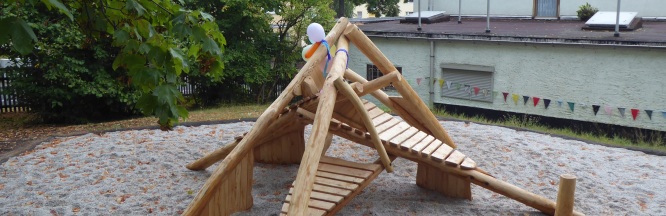 Das Bild zeigt ein Spielgerät aus Holz im Garten geschmückt mit Luftballons. 