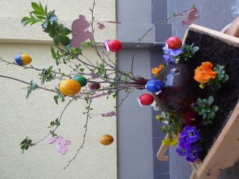 Eine Vase mit Forsythienzweigen wurde mit bunten Ostereiern geschmückt