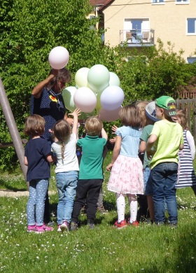 Kindergartenkinder bekommen bunte Luftballons ausgehändigt