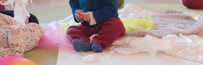 Hände eines Kindes und einer erwachsenen Person spielen mit verschiedenen Materialien